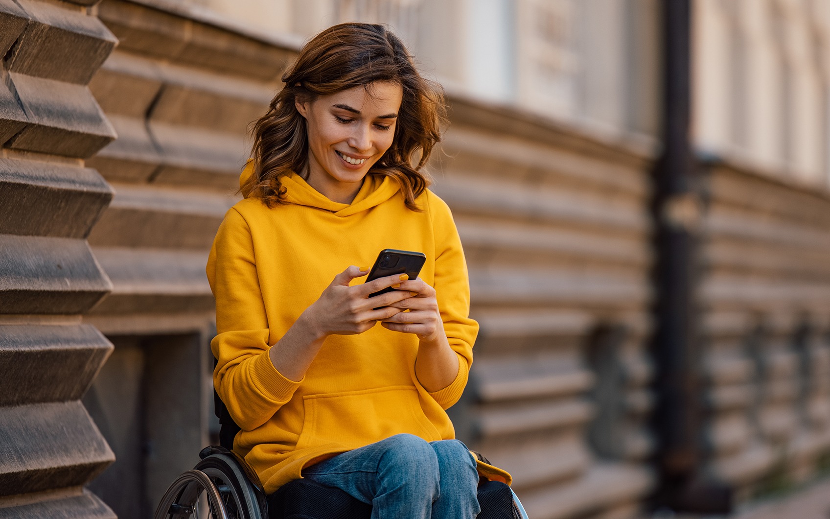 Frau in Rollstuhl mit Handy