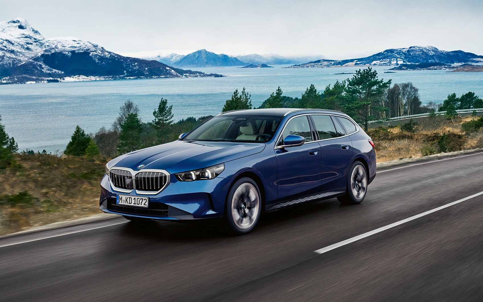 Studioaufnahme eines BMW 5er Touring in der Farbe Blau mit Fokus auf die linke Fahrzeugseite und den linken Scheinwerfer