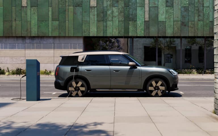 Alt-Text: Grauer Elektro-SUV von Mini an Ladesäule auf städtischem Gehweg.