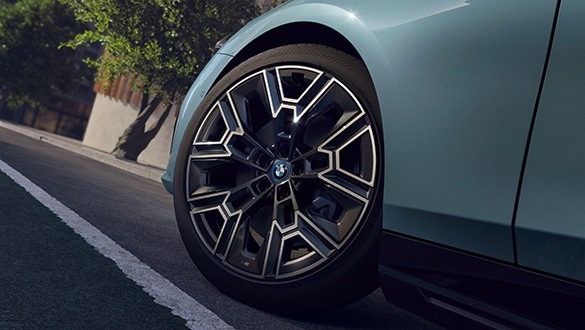 Vorderrad des BMW i5 Touring, geparkt am Bordstein, in modernem Design in Stadtszenerie