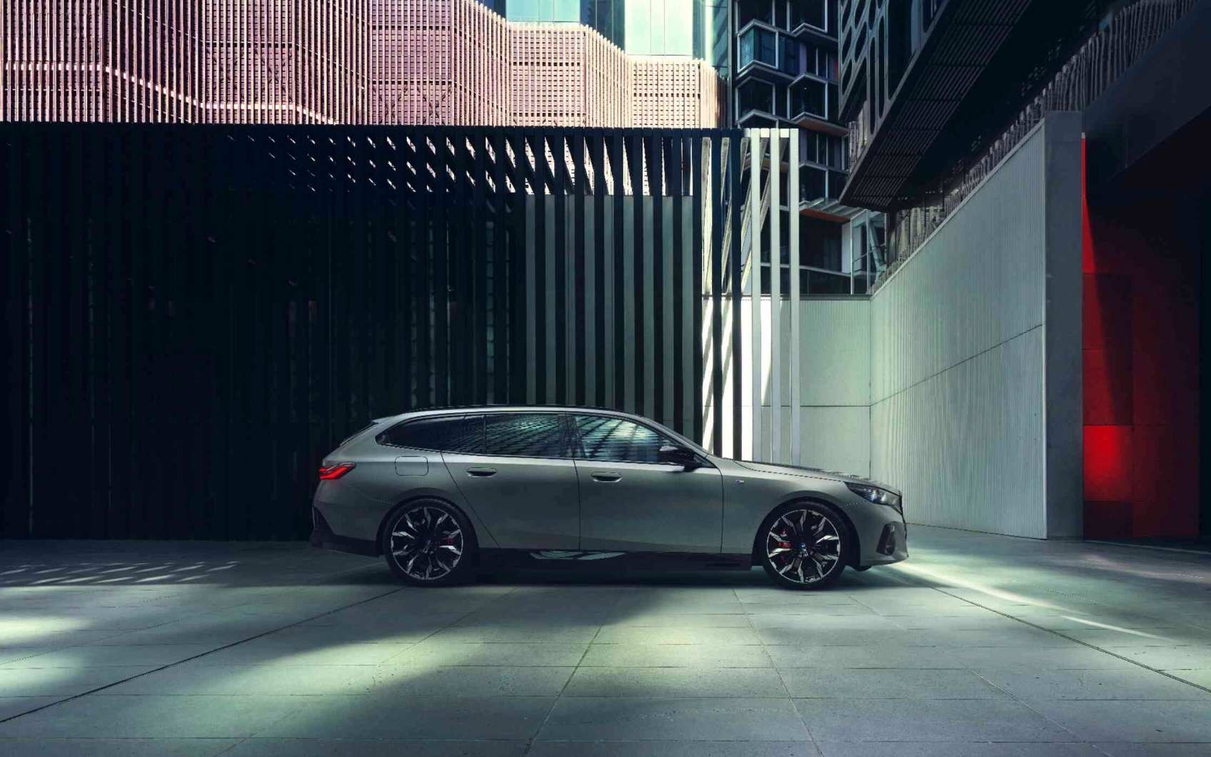 Grüner BMW i 5 Touring mit stylisher Stadt im Hintergrund
