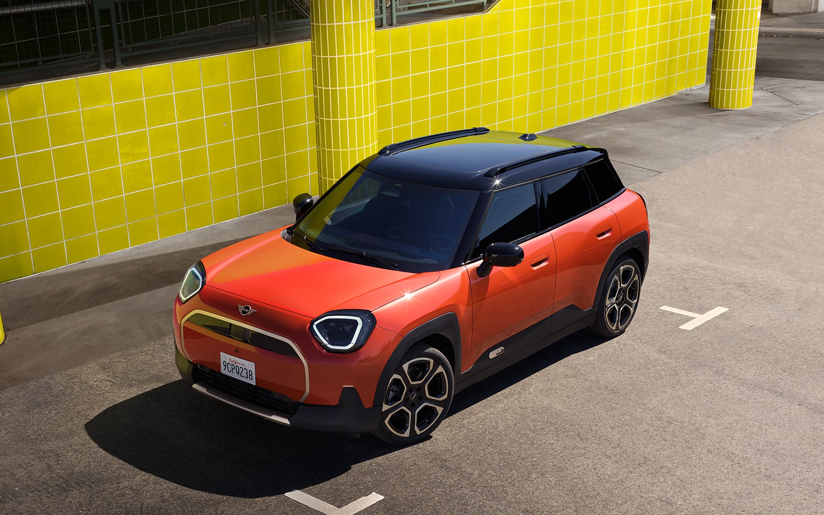 Alt-Text: Roter Mini SUV mit schwarzem Dach auf einem Parkplatz vor gelber Kachelwand.