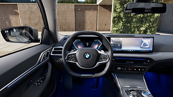 Cockpit des BMW 4er Gran Coupé aus Sicht des Fahrers mit Blick auf eine Gebäudeeinfahrt und einer mit Holz verkleideten Wand