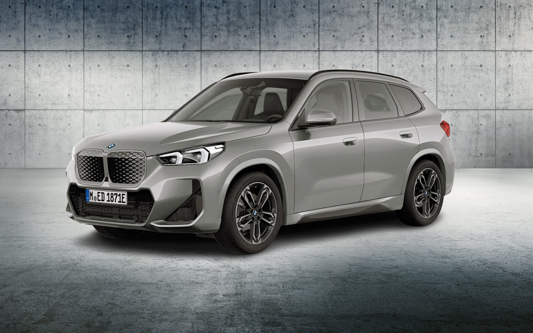 Silberner BMW iX1 vor Betonwand