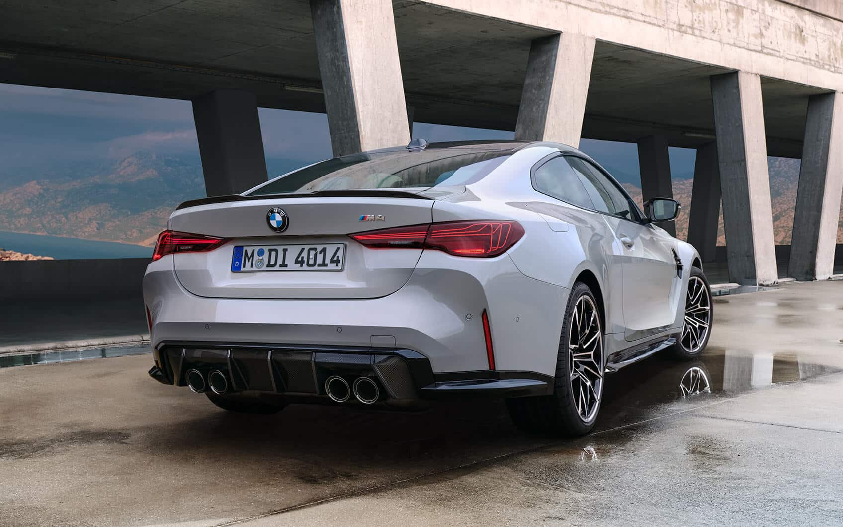 Weißes BMW M4 Coupé in Heck-Seitenansicht unter Betonbrücke